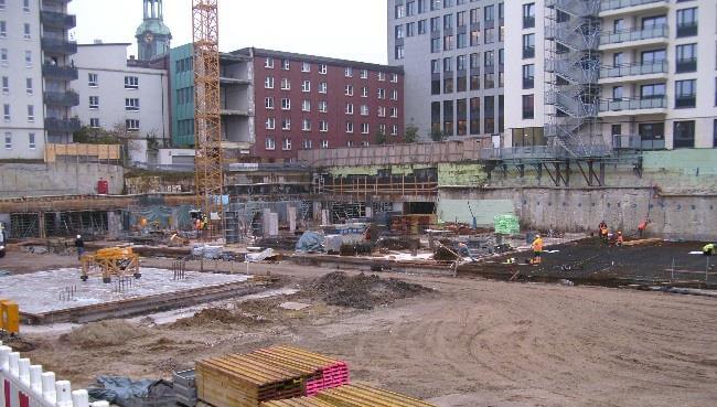 Blick auf die Baustelle des Alstercampus, 2. Bauabschnitt, mit modernen Gebäudestrukturen und umgebender Landschaft.