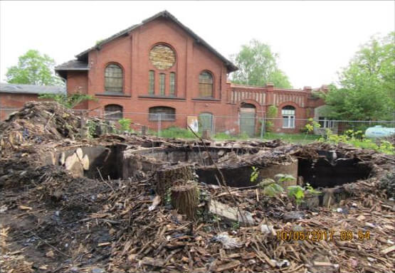 Verfallenes Gebäude des ehemaligen Gaswerks in Königs Wusterhausen, umgeben von wildem Grün und urbanem Charme.