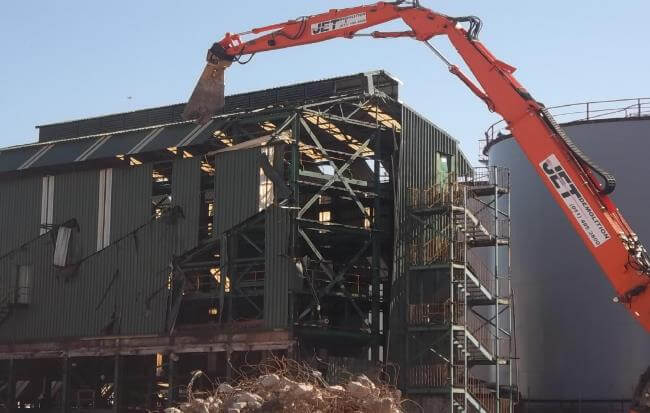 Demontagearbeiten an einem Gebäude in der Hainan Road, Durban, mit Baumaschinen und Baustellenabsperrungen.