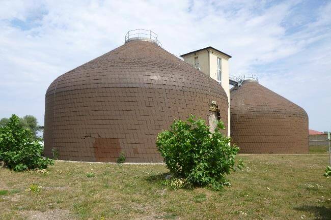 Blick auf die neu errichteten Betriebsgebäude der Kläranlage Schkopau, umgeben von Baustellenmaterial und Natur.